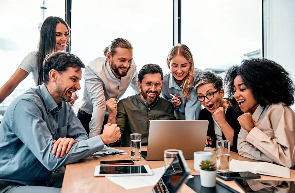 A group of people huddled around someone solving a problem at work