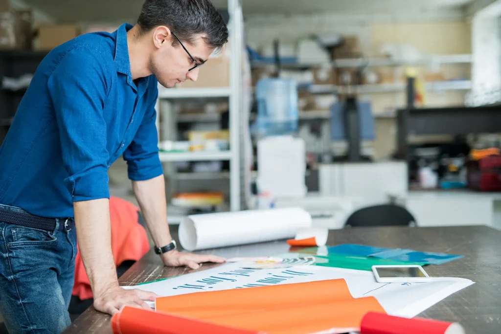 Young adult in a print shop looking over printed material